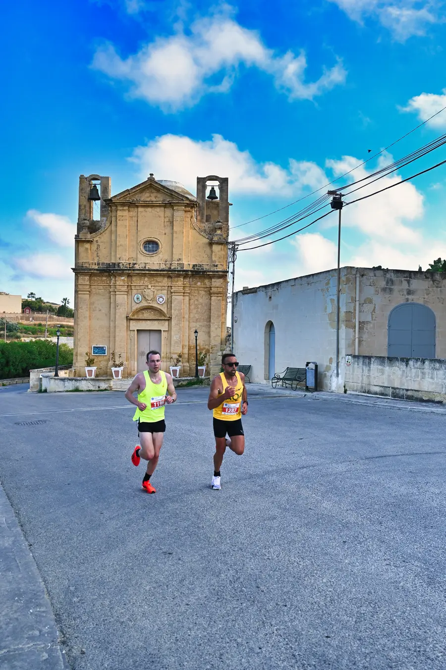 Joseph Arundel and Charlton Debono running past a village chapel in the 2025 half marathon