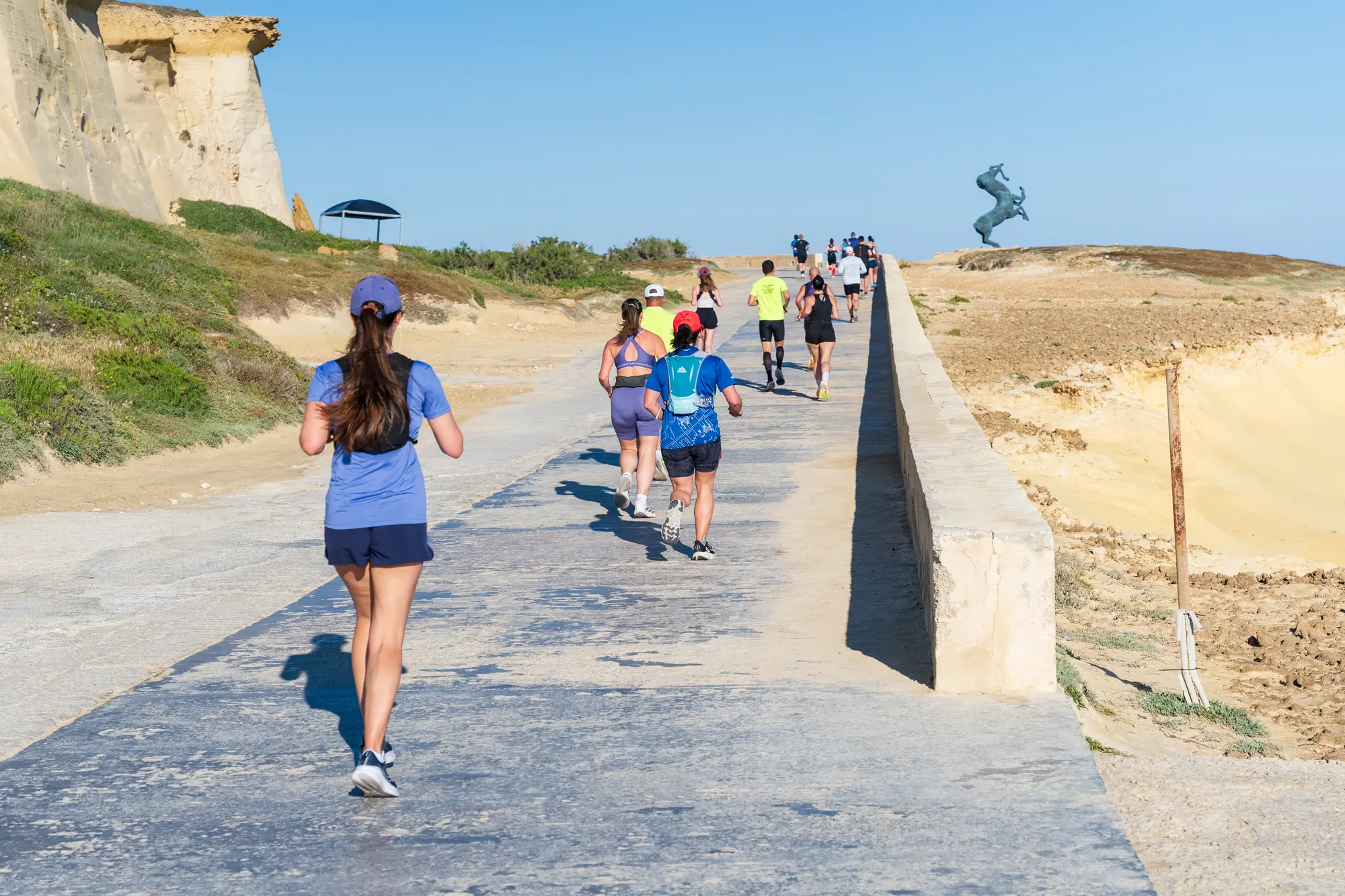 Runners on the coastal path by the sea in Gozo