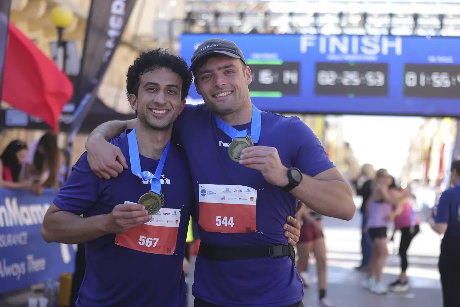 Two finishers showing off their medals at the finish